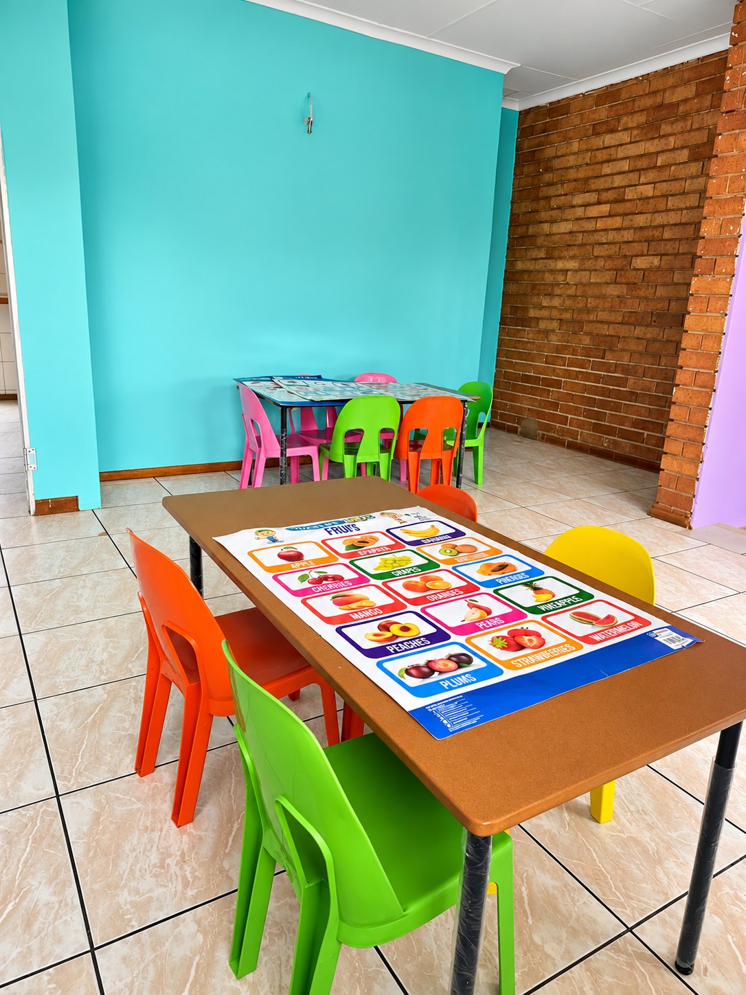 A bright teal classroom with colourful tables and chairs